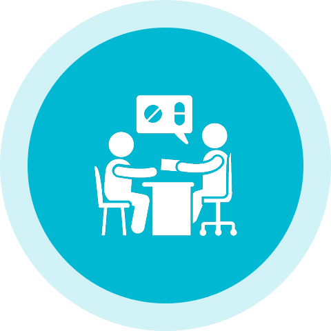 Two people sitting at a table with one of them talking to another person.